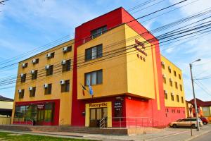 ein farbenfrohes Gebäude auf einer Straße mit einem Auto davor in der Unterkunft Hotel Alexandra in Timişoara