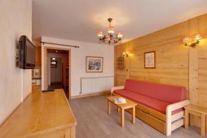 sala de estar con sofá rojo y TV en Vacancéole - Résidence Les Bleuets en Les Deux Alpes