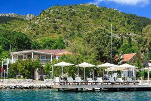 a house with a dock with chairs and umbrellas on the water at Losta Sahil Evi - Adults Only +12 in Selimiye