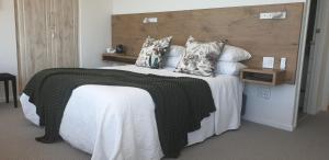een slaapkamer met een groot bed met witte lakens en kussens bij Villa Vista - 4 Star Self Catering or Room Only - No Loadshedding in Mosselbaai