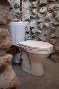 a white toilet sitting next to a stone wall at Etosha Trading Post Campsite in Okaukuejo