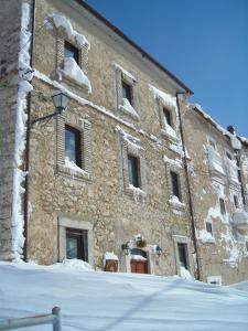 a large stone building with snow on the windows at La Locanda delle Streghe - Relais Ristorante in Castel del Monte