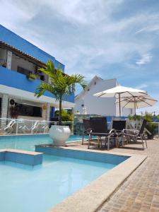 a pool with chairs and umbrellas next to a building at Pousada Maresia Costa Azul in Rio das Ostras