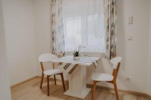 una mesa y sillas blancas en una habitación con ventana en Peter Lamster Top3, en Frauenkirchen
