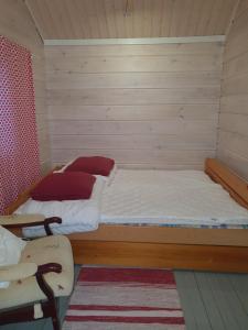 a bedroom with two beds and a chair in it at Sammalkalliontie 83 Lodge in Kinnula