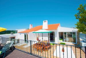 a house with an umbrella and chairs on a deck at Villa São Paulo by Algarve Vacation in Albufeira