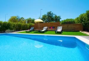 a swimming pool with two chairs and an umbrella at Villa São Paulo by Algarve Vacation in Albufeira