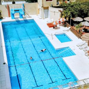une grande piscine avec deux personnes dans l'eau dans l'établissement San Remo Resort Hotel, à Santa Teresita