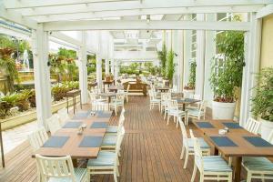 a patio with wooden tables and chairs in a greenhouse at Apartamento com varanda no IL Campanário Resort in Florianópolis