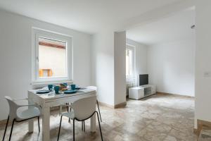 une salle à manger blanche avec une table et des chaises dans l'établissement Rose Apartment by Quokka 360 - refined two-bedroom apartment with garden, à Lugano