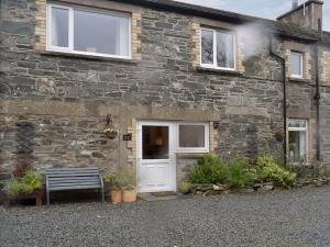 GlenluceにあるDairy Cottage Dog friendly cottage with private courtyard and wood burner in Dumfries and Galloway - Contractors welcomeの白い扉とベンチのあるレンガ造りの家