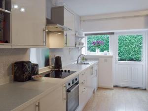 a kitchen with white cabinets and a sink and a window at Dairy Cottage Dog friendly cottage with private courtyard and wood burner in Dumfries and Galloway - Contractors welcome in Glenluce