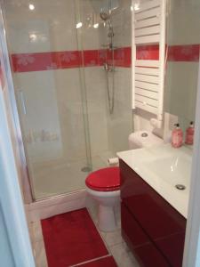 uma casa de banho com um WC vermelho e um chuveiro em APPART MER CALME ET ENSOLEILLEE em Le Grau-du-Roi