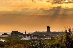 a view of a city at sunset with rays of sunlight at Vakantiewoning Weverijstraat met strandcabine in Domburg