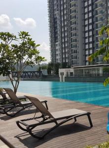 two lounge chairs sitting next to a swimming pool at Cikta Homestay at Southville City Savanna Suite in Kampong Tangkas +3 photos