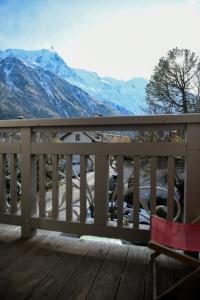 une chaise sur une terrasse avec des montagnes en arrière-plan dans l'établissement Appart'Hotel Aiguille Verte & Spa, à Chamonix-Mont-Blanc