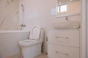 a white bathroom with a toilet and a sink at Stayokay Sattahip - Flat House in Sattahip