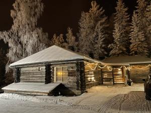 MuurameにあるRiihitulkku Lodgeの雪中のクリスマスライト付きのログキャビン