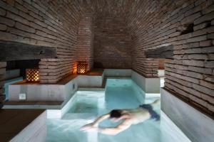 
a man is swimming in a bathtub in a swimming pool at Azur Real Hotel Boutique in Córdoba
