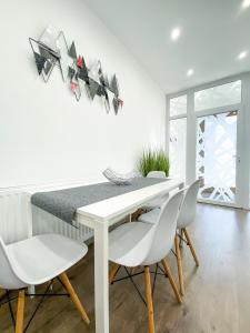 uma sala de jantar branca com uma mesa e cadeiras brancas em Főtér apartman II. em Villány