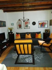 a living room with a black couch and orange pillows at Planinska kuća MAK in Jahorina
