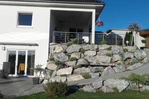 a stone retaining wall in front of a house at Allgäu gemütliche, moderne Wohnung mit Garten-Pool in Argenbühl