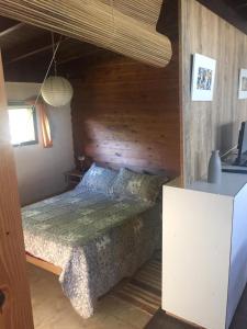 1 dormitorio con 1 cama con pared de madera en CABAÑA ÚNICA en Miramar