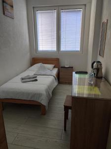 a bedroom with a bed and a desk and two windows at Villa Ivanovi in Ohrid