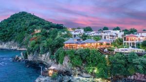 a resort on a cliff next to the water at Cap Maison Resort & Spa in Cap Estate