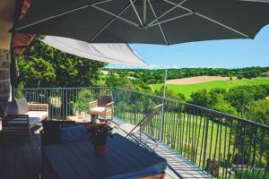 a balcony with an umbrella and a table and chairs at La Fournial in Lunac