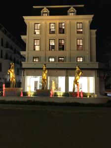 un edificio con estatuas delante de él por la noche en SAOLA Apartment & Hotel en Dong Ra