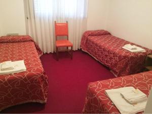 een hotelkamer met 2 bedden en een rode stoel bij Hotel Ser-Mar in San Bernardo