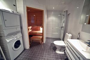 a bathroom with a toilet and a sink and a washing machine at JK Apartment Jannela in Lapua