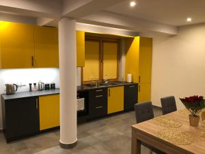 a kitchen with yellow and black cabinets and a table at Osada Witów - Dolina Złota in Witów