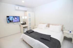 a white bedroom with a bed and a tv at بيت السليمي التراثي in Shaqra