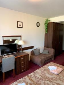 a hotel room with a couch and a desk with a television at Apartamenty Arka Medical Spa **** in Kołobrzeg