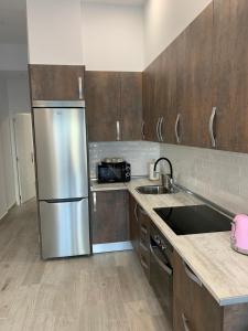 a kitchen with a stainless steel refrigerator and wooden cabinets at T-Homes - Fuencarral in Madrid