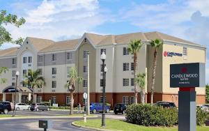 a large building with palm trees in a parking lot at Candlewood Suites Melbourne-Viera, an IHG Hotel in Viera
