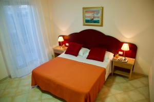 a bedroom with a large bed with red pillows at Hotel Teti in Torre Mozza
