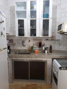 une cuisine avec des placards blancs et un comptoir dans l'établissement Apartamento Cabo Frio, à Cabo Frio
