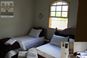 a bedroom with two beds and a window at Vila Marias in Ouro Preto