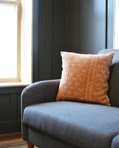a blue couch with an orange pillow in a room at The Flying Steamshovel Inn in Rossland