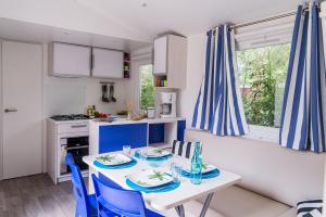 a kitchen with a table and blue chairs in a kitchen at MOBIL HOME 6 personnes TOUT CONFORT in Saint-Cyprien