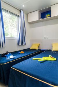 two twin beds in a room with blue sheets at MOBIL HOME 6 personnes TOUT CONFORT in Saint-Cyprien
