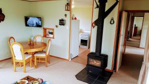 a living room with a wood stove and a table at Little Red Riding Hood in Reefton