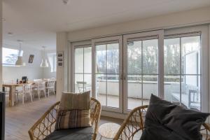 een woonkamer met glazen deuren en een eetkamer bij Duinhof Dishoek Luxe appartementen in Dishoek