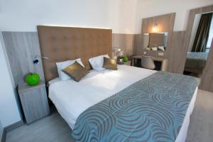 a bedroom with a large white bed with a large headboard at Hotel Atlanta Knokke in Knokke-Heist