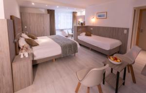 a hotel room with two beds and a table and chairs at Hotel Atlanta Knokke in Knokke-Heist