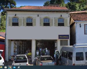 un edificio bianco con macchine parcheggiate di fronte di Vila Marias a Ouro Preto