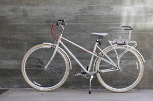 Una bicicleta blanca con una canasta aparcada contra una pared en H2hotel, en Healdsburg